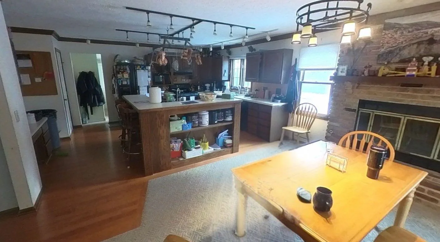 Kitchen and fireplace area before renovation with dark wood cabinets, wood flooring, and central island