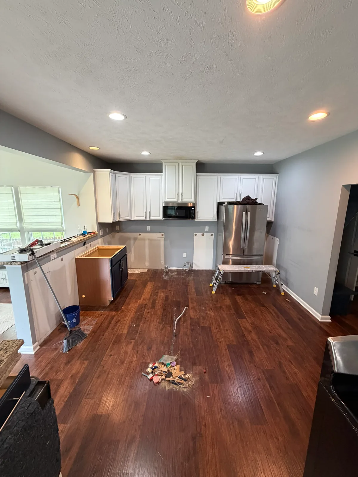 Kitchen during gut remodel with lower cabinets removed, exposed wall areas, construction tools, and an unfinished island